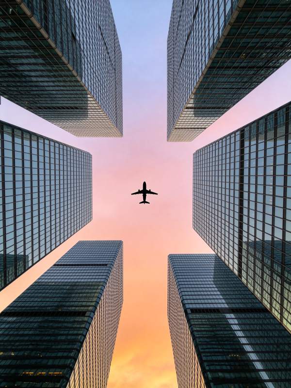 高楼林立间飞行的客机剪影图片