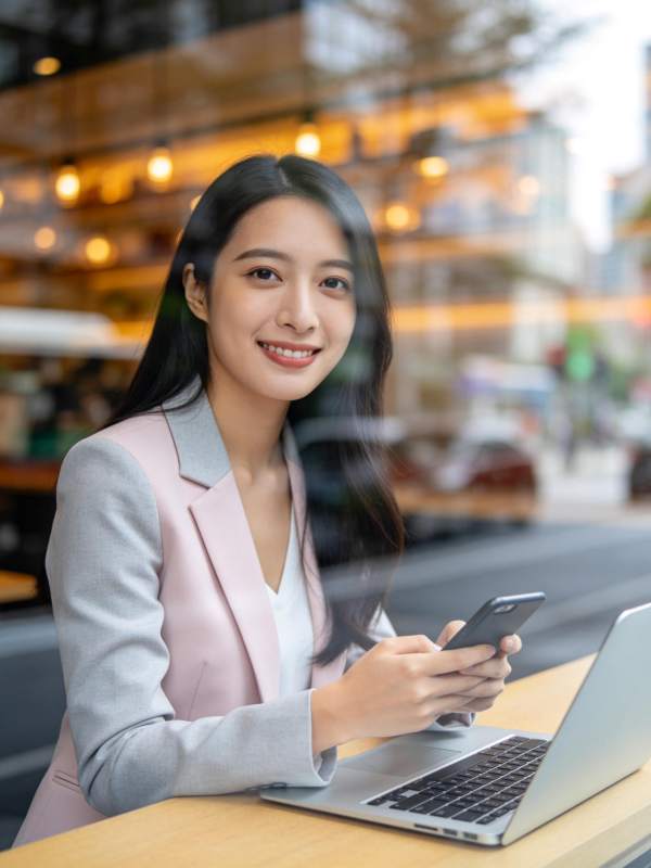 职场女性窗边使用手机与笔记本电脑工作图片