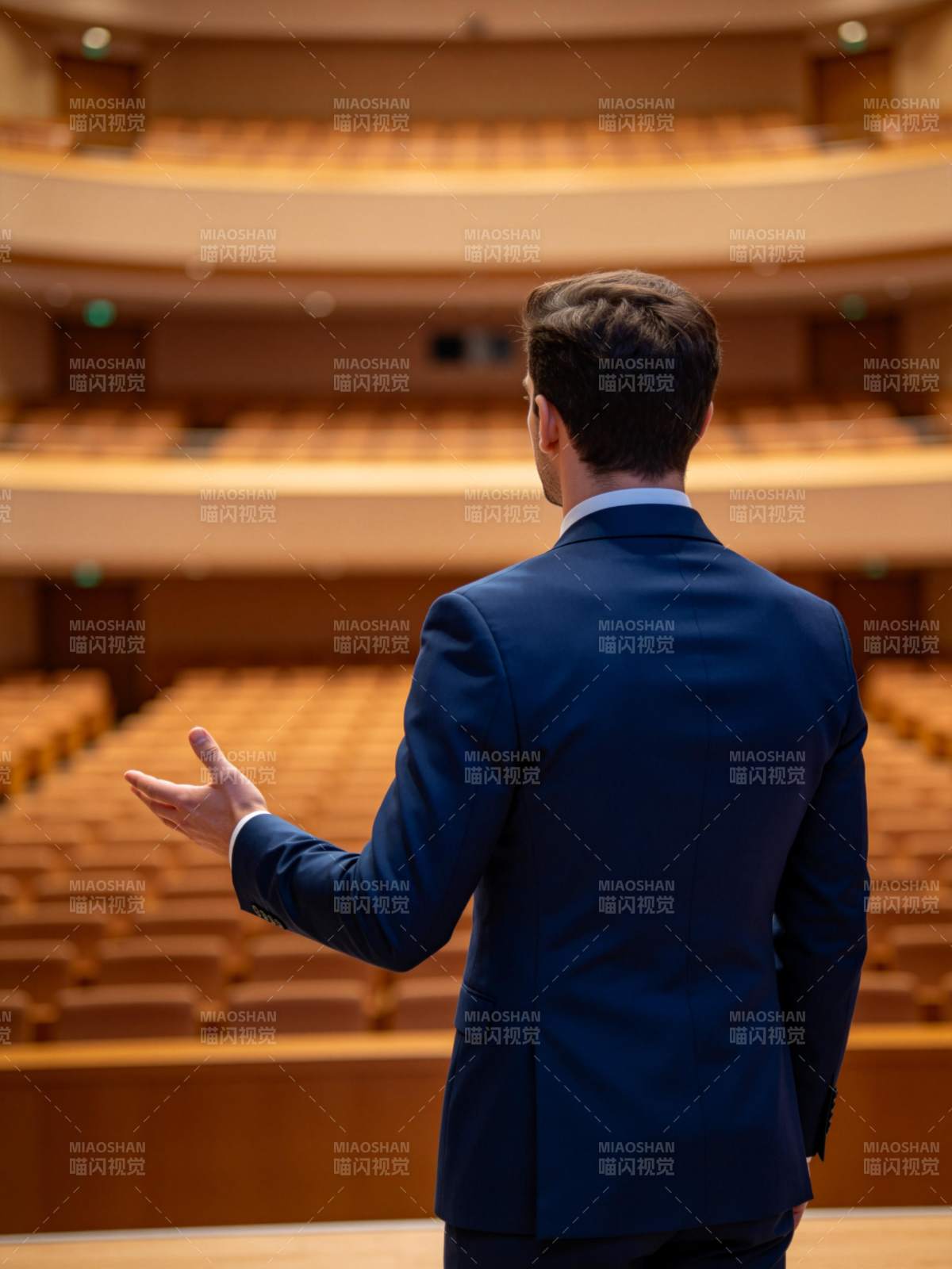 男士背对镜头在空旷礼堂演讲手势示意图片