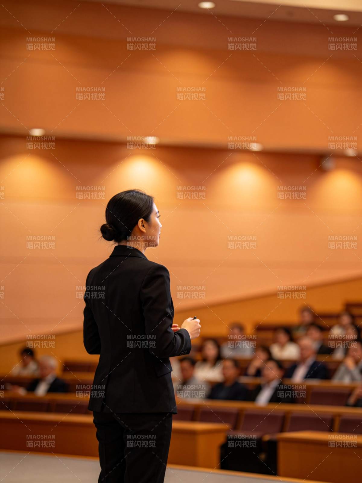 女性演讲者在阶梯教室面向听众演讲图片