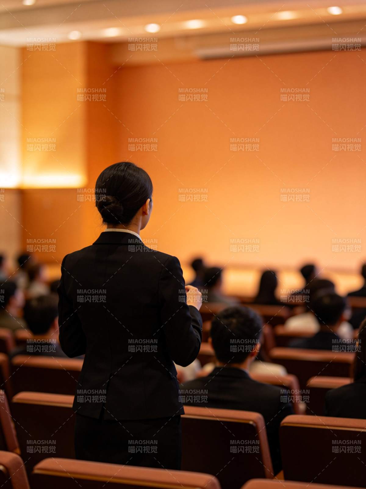 女性演讲者背对观众在会议厅进行报告图片