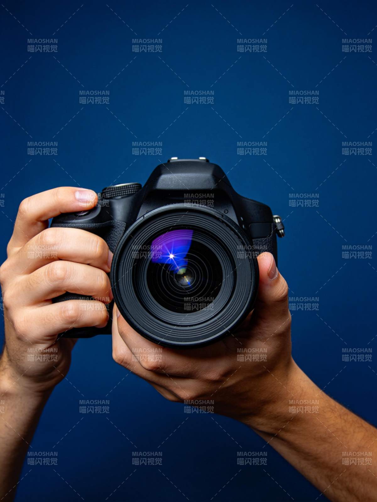 双手持单反相机对准镜头特写图片