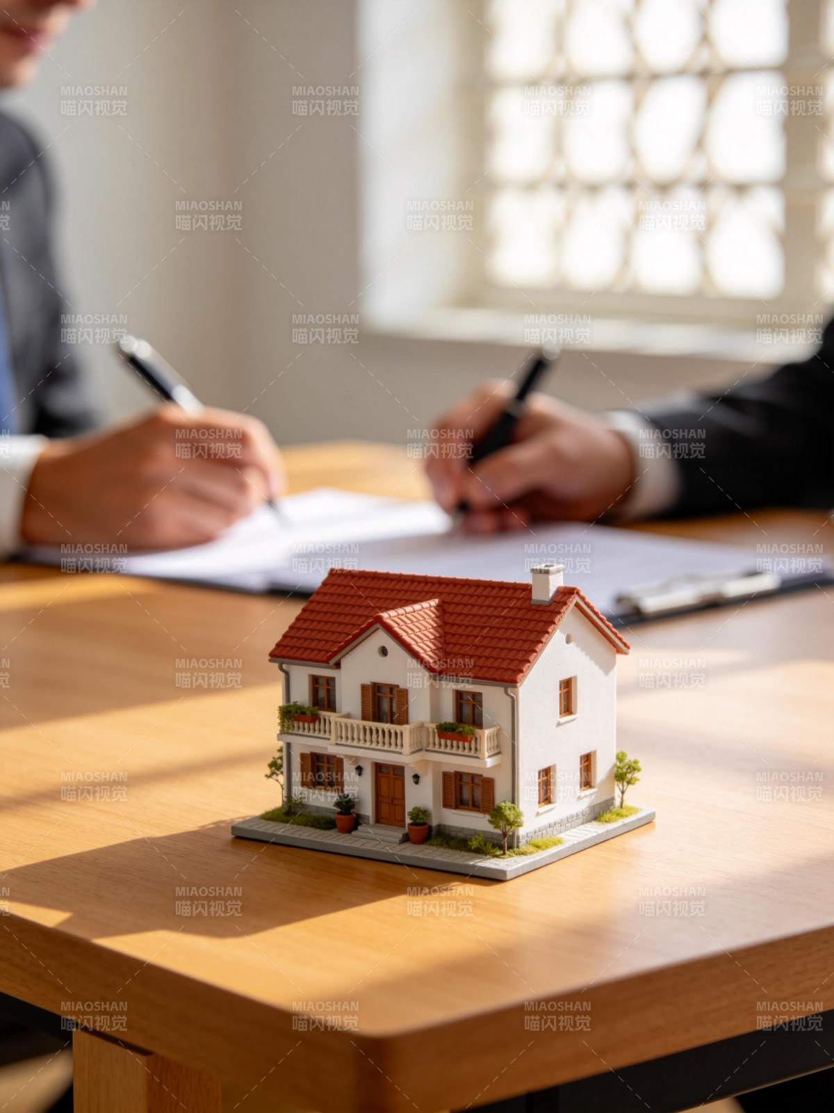 桌上房屋模型旁两人签署文件场景图片