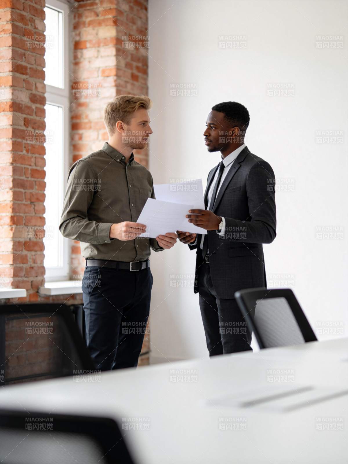 两位男士在办公室内讨论文件内容图片