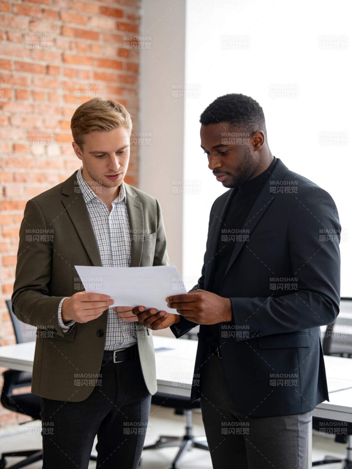 两位男士在办公室共同审阅纸质文件图片