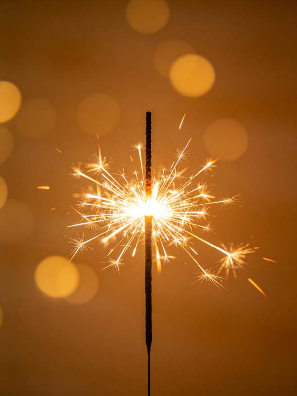 点燃的烟花棒在暖光背景中绽放火花图片