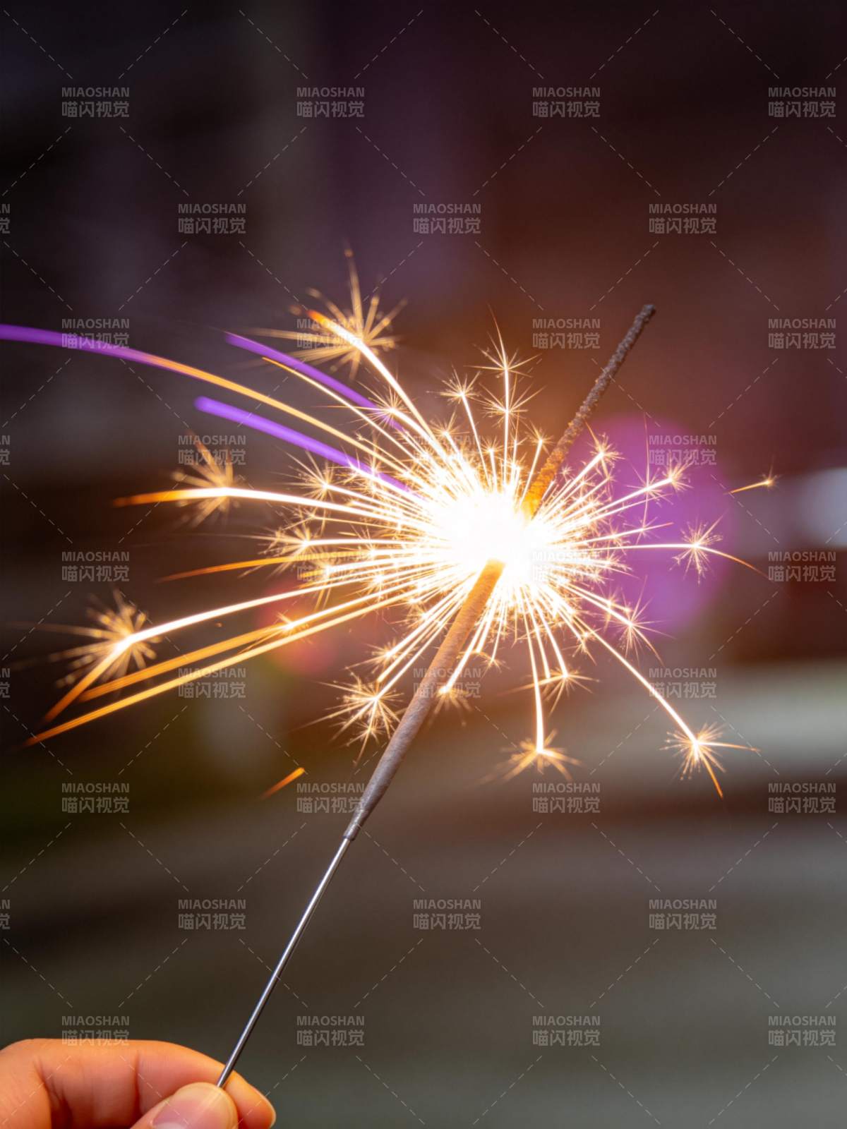 手持点燃的烟花棒发出明亮火花图片
