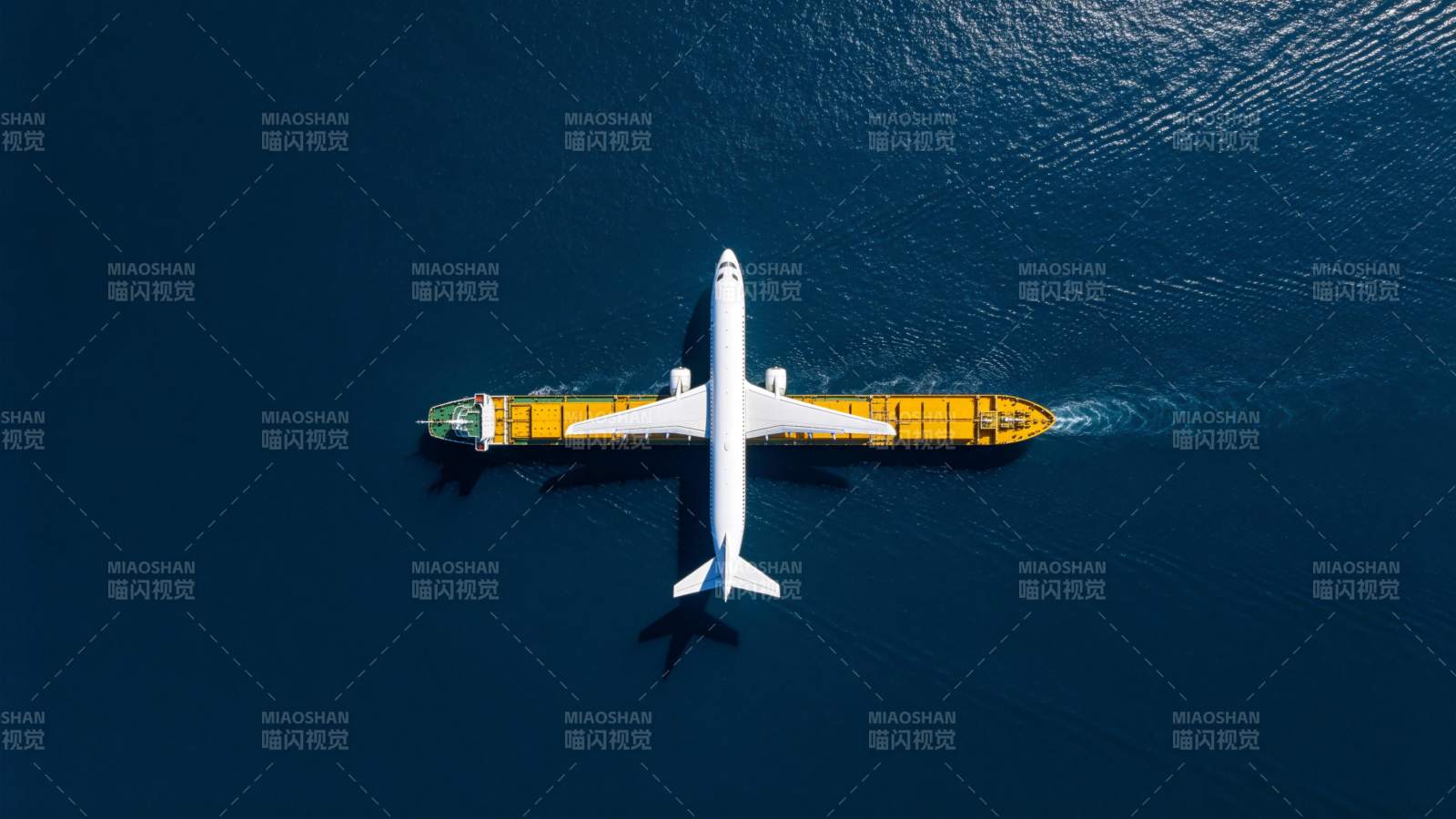 飞机与货轮在深蓝海面并行航行图片