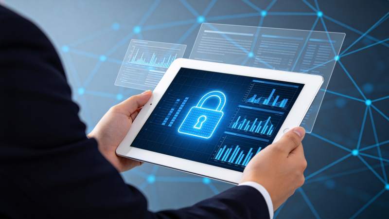 手持平板显示蓝色锁形安全图标与数据图表图片