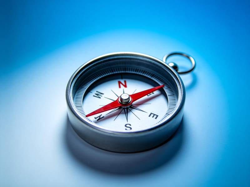 金属指南针置于蓝色背景上清晰特写图片