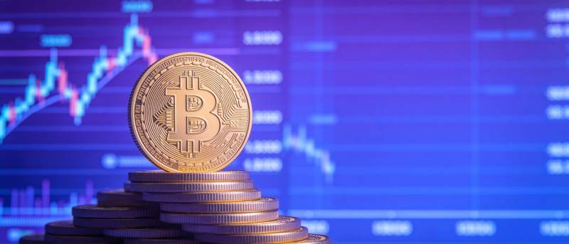 比特币金币堆叠于金融图表背景前图片