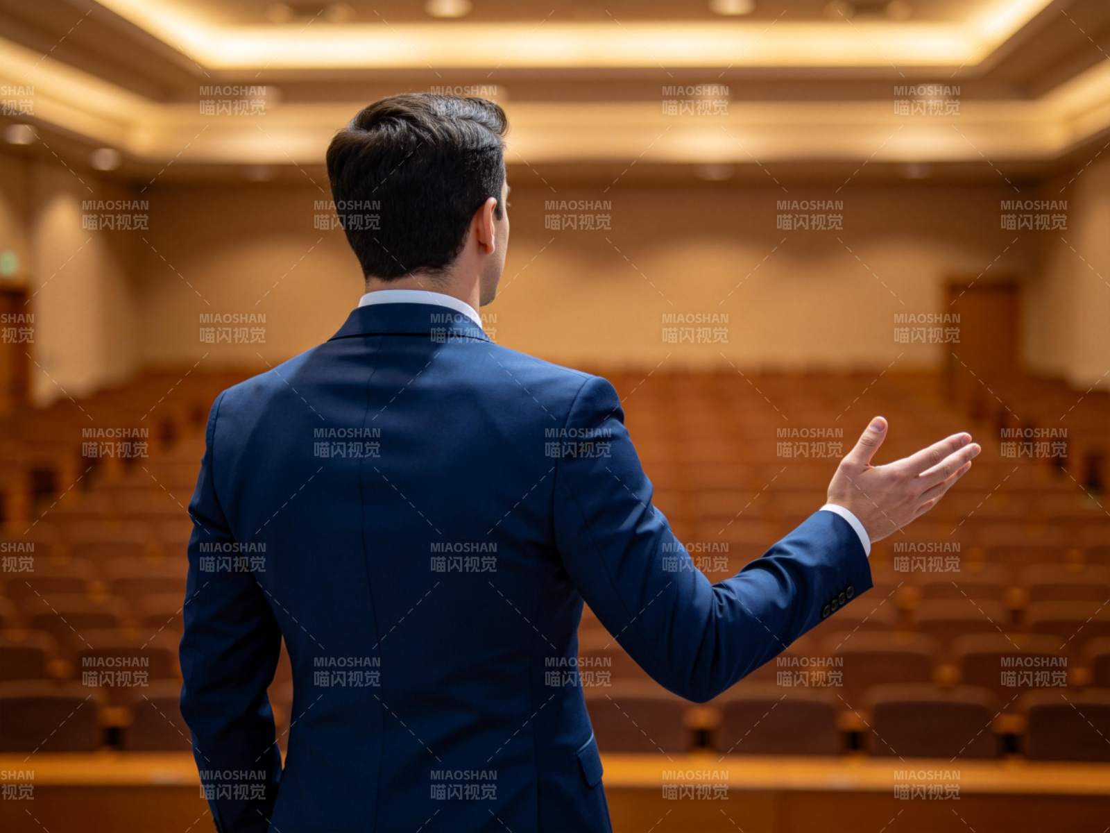 男士背影在空旷会议厅中演讲手势示意图片