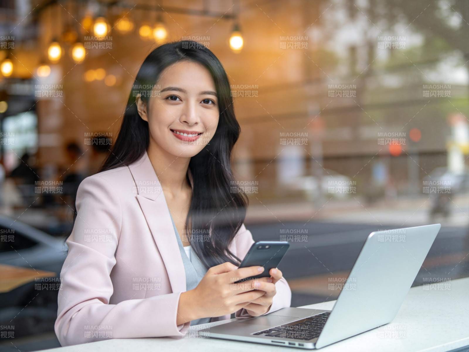 女性在咖啡馆使用手机与笔记本电脑工作图片