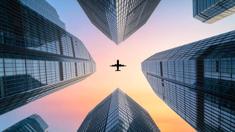 城市高楼间飞行的客机剪影图片