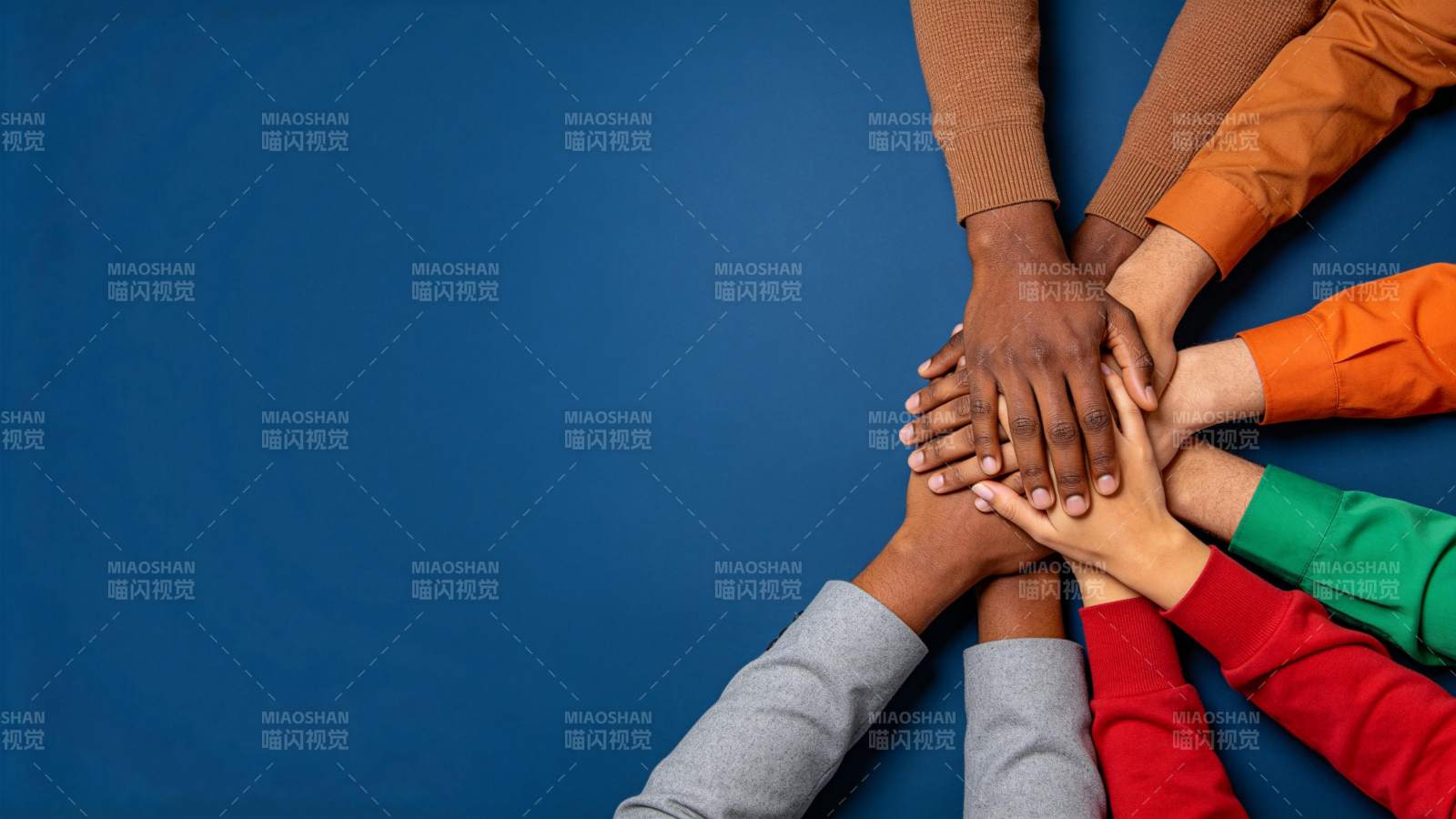 多只不同肤色手臂叠放形成团结手势图片