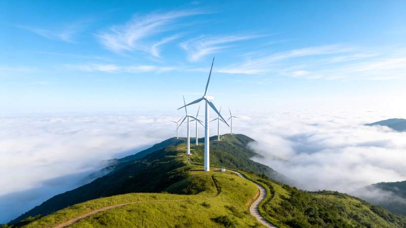 山顶风力发电机群矗立云海之上图片