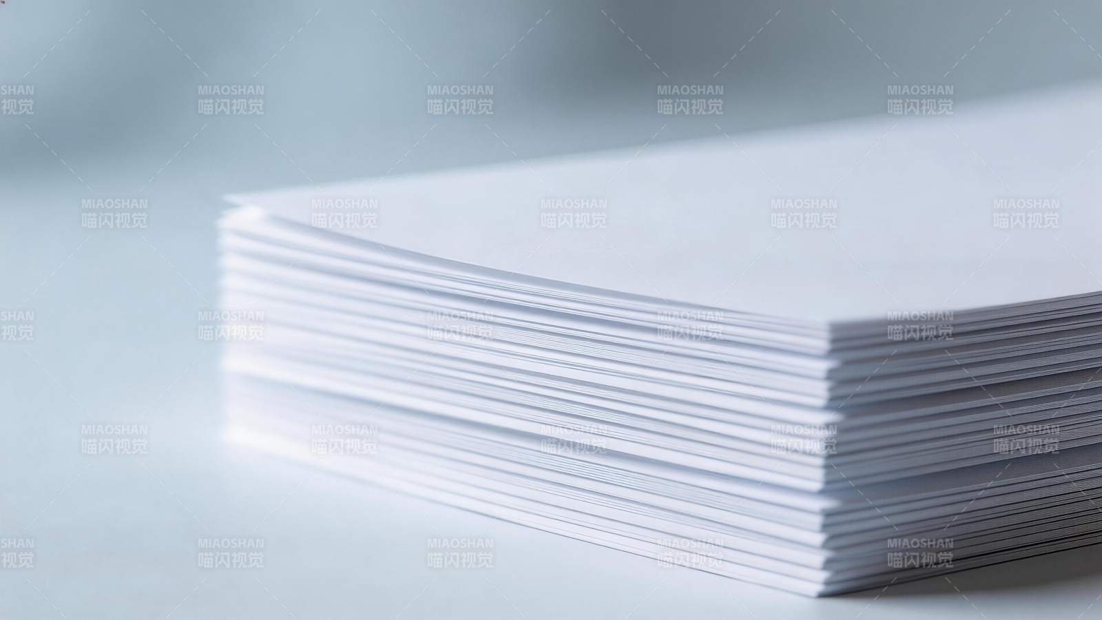 一叠整齐白色打印纸放置于浅色桌面图片