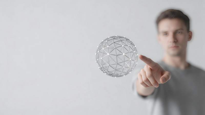 男子手指触碰悬浮金属网格球体图片