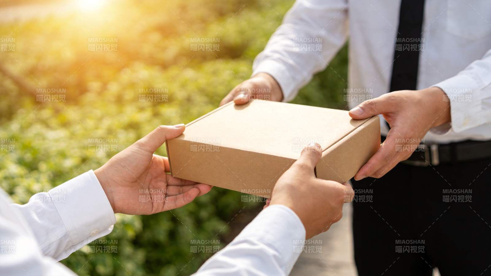 两人在户外交接棕色纸盒包裹图片