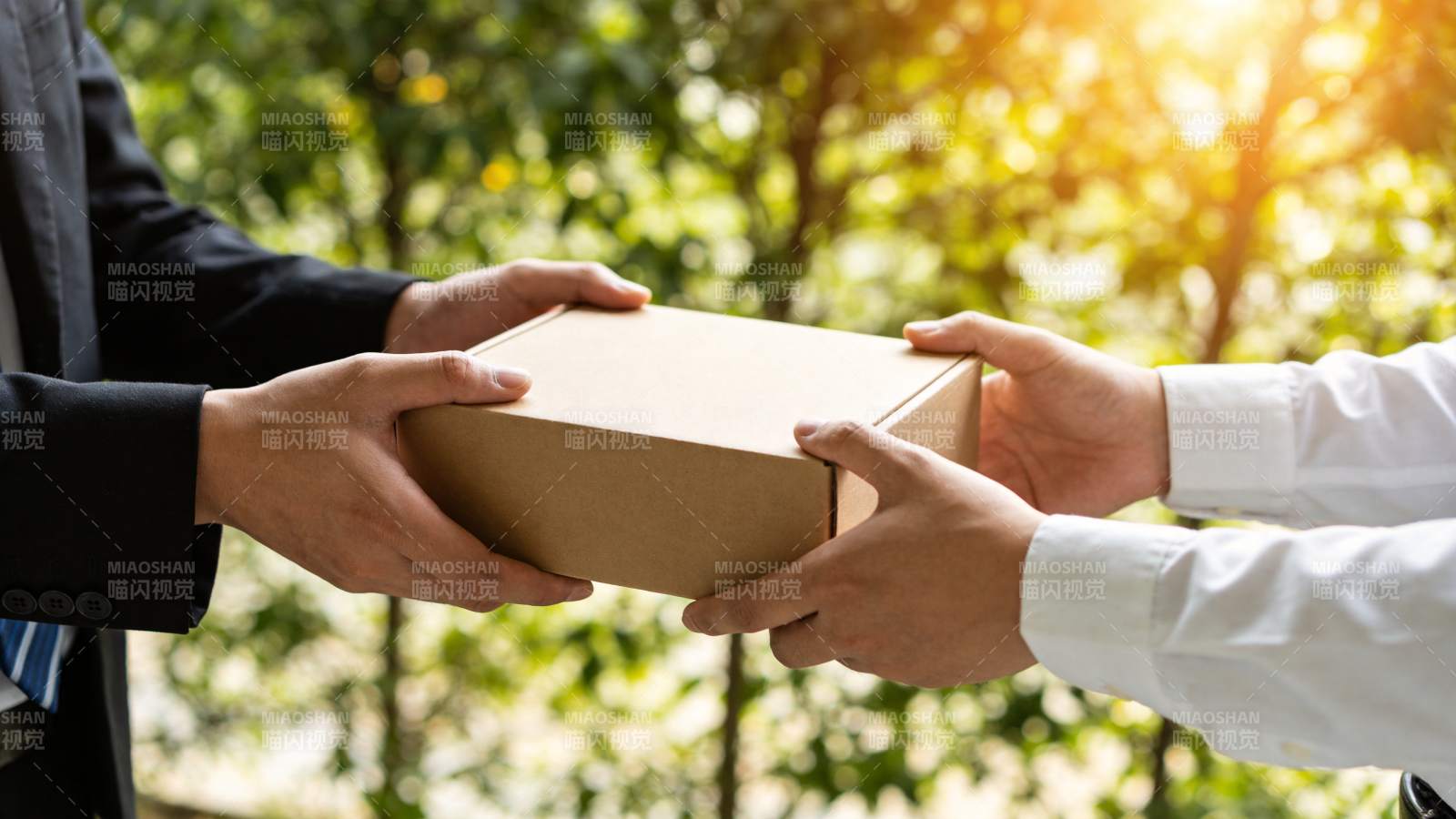 两人交接棕色纸盒包裹的特写场景图片