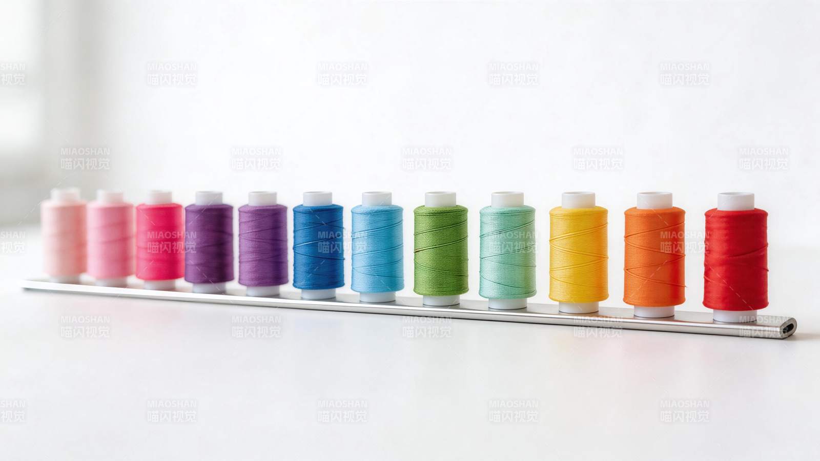 一排彩色缝纫线轴整齐排列在金属支架上图片