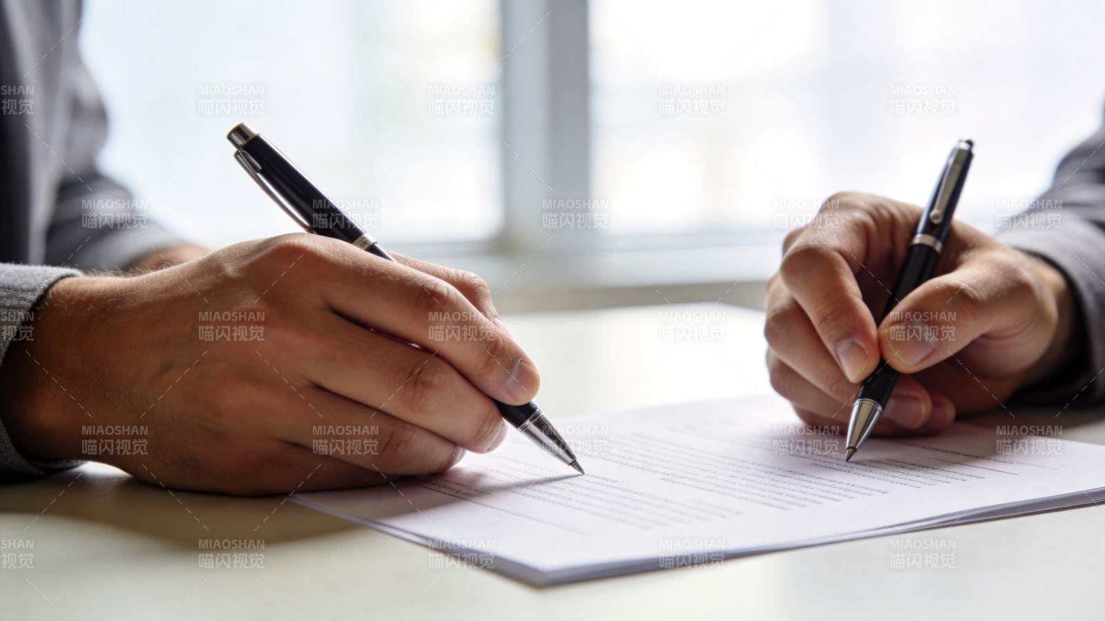 两人手持钢笔在文件上签字的特写场景图片