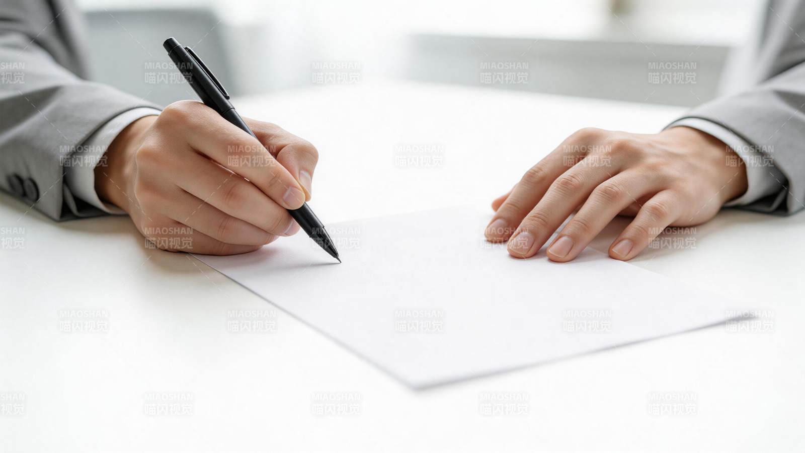 身穿灰色西装的人正在白纸上用黑色签字笔书图片