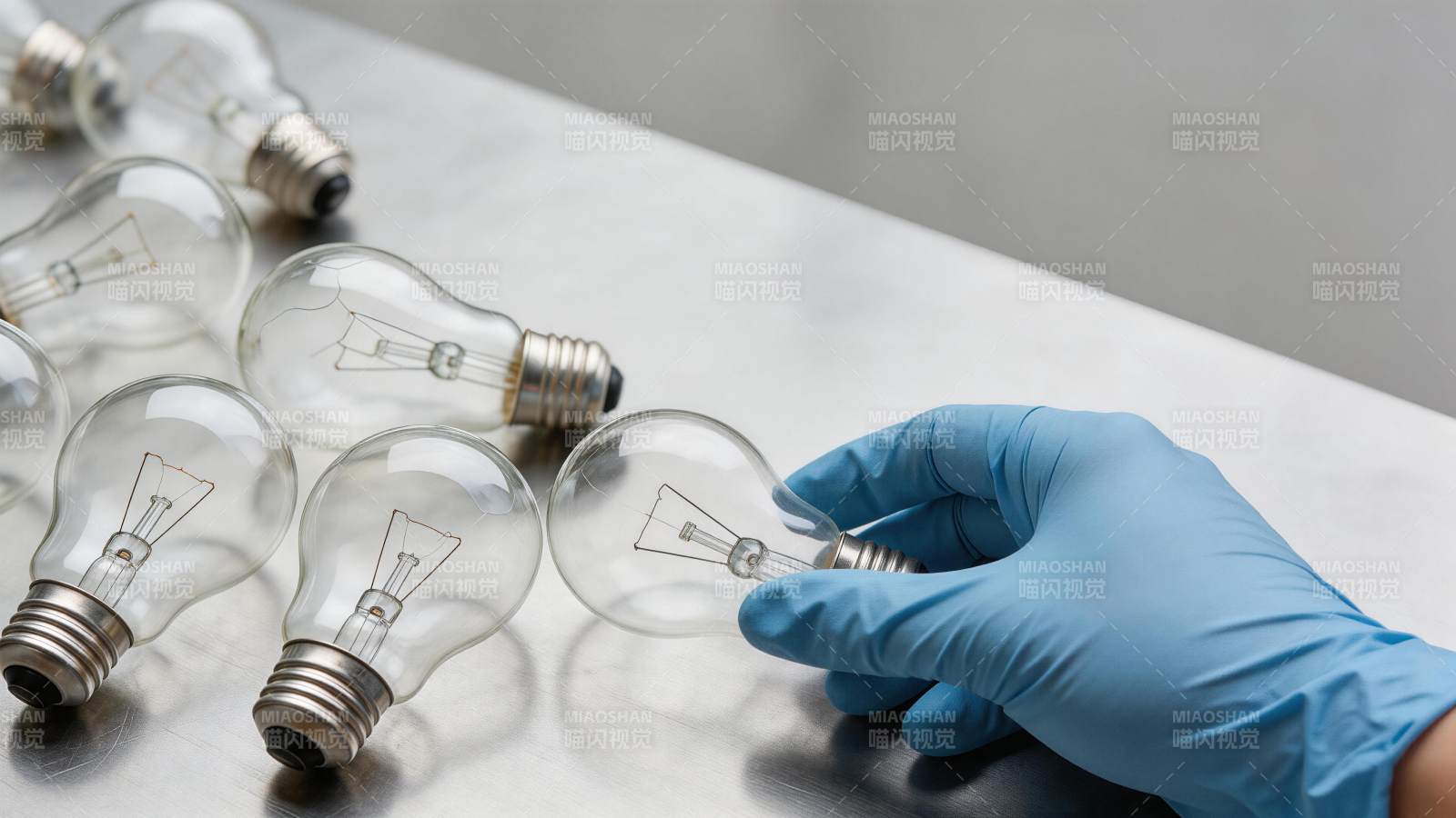 戴蓝色手套的手拿起白炽灯泡检查图片