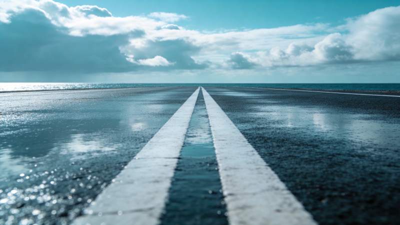 湿漉漉的柏油路延伸至海天交界处图片