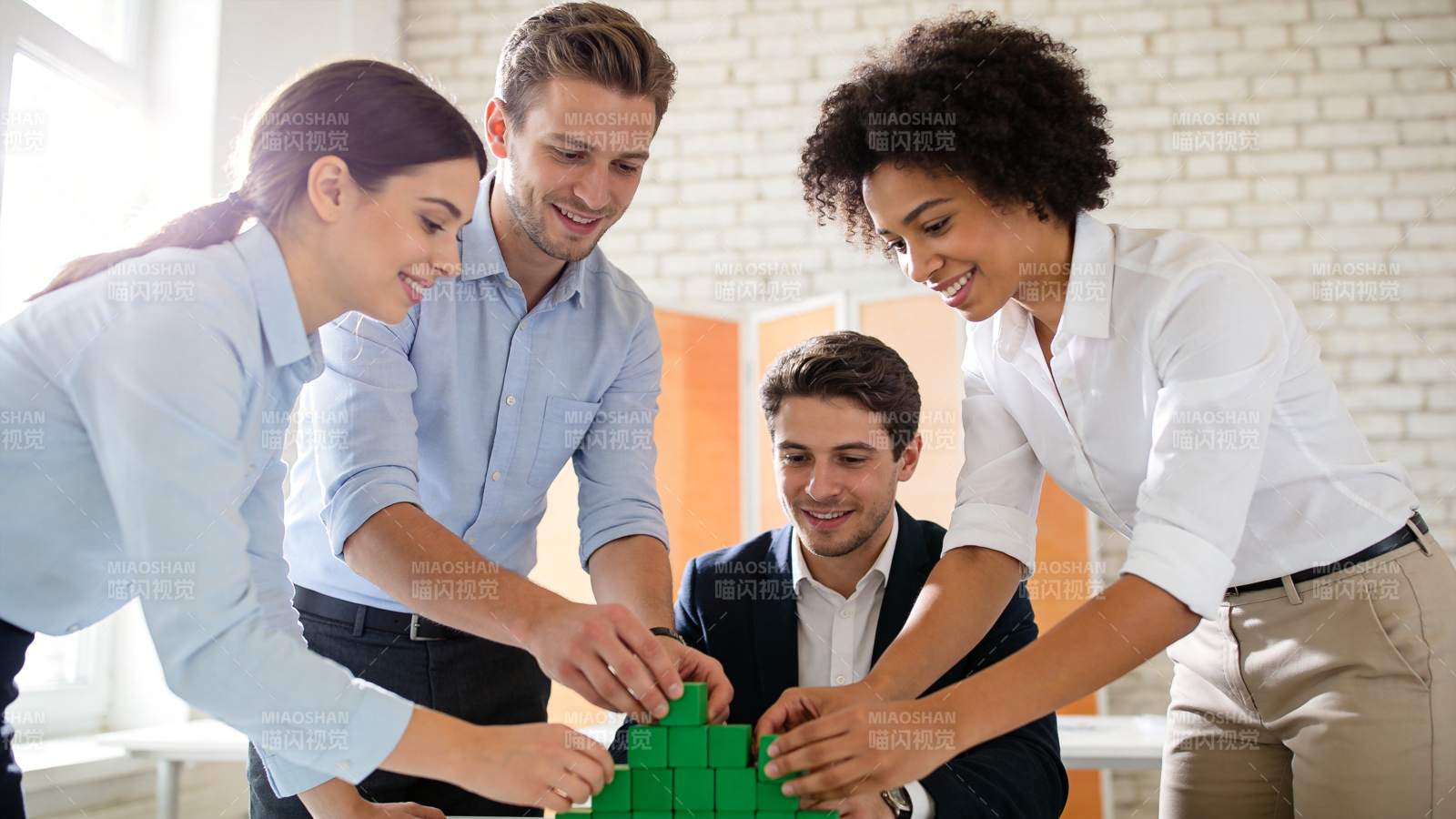 四人协作搭建绿色积木模型场景图片