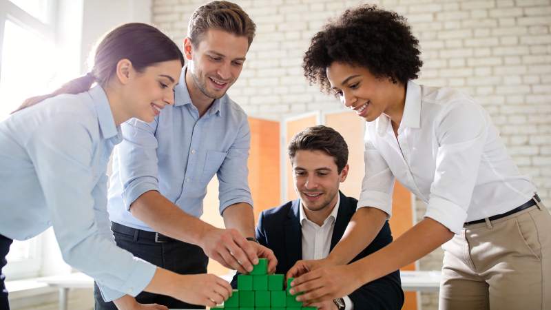 四人协作搭建绿色积木模型场景图片