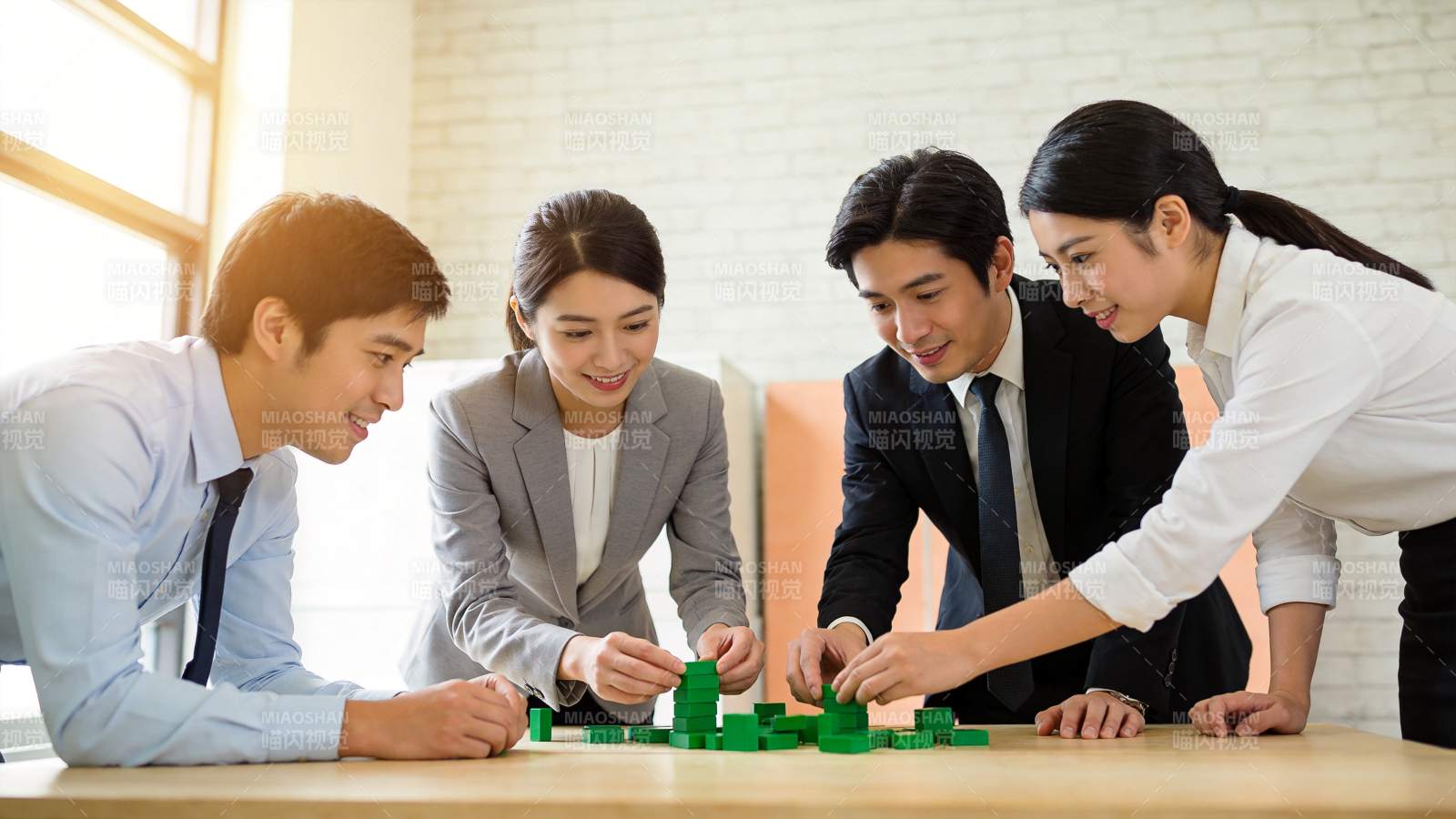 四人围桌合作搭建绿色积木模型图片