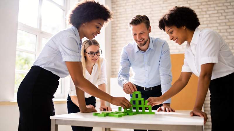 四人协作搭建绿色积木模型场景图片