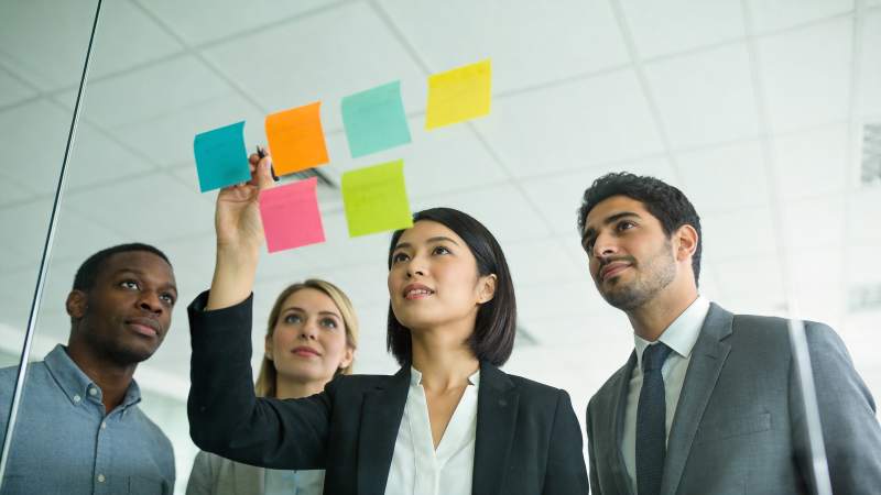 职场人员在玻璃板前讨论彩色便签内容图片