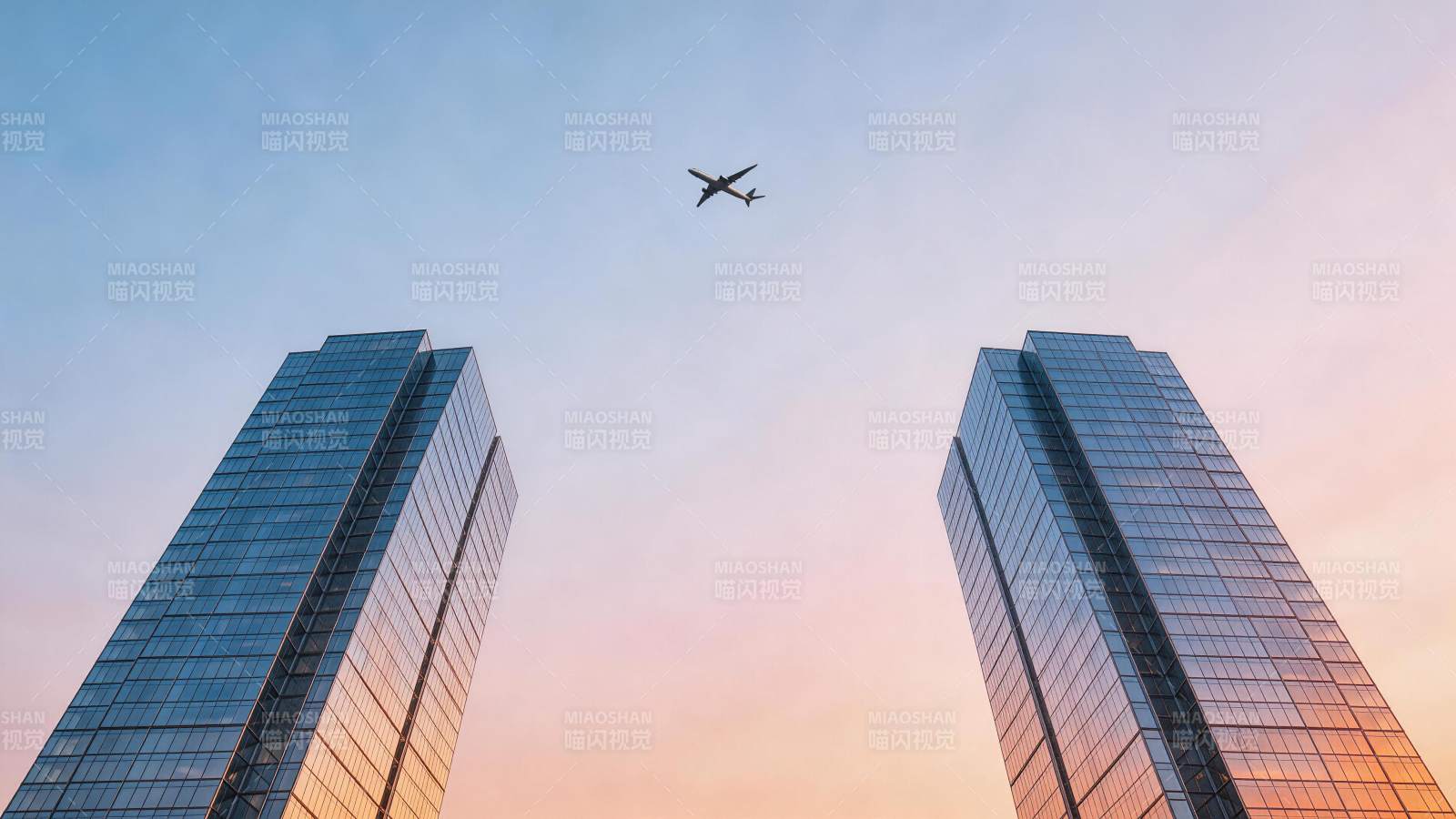 双塔高楼间飞行客机与渐变天空图片