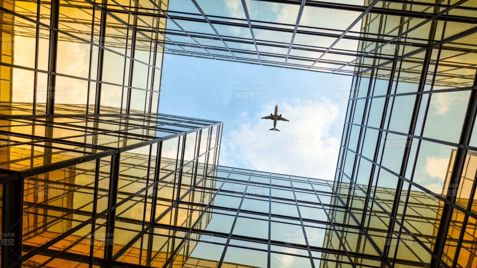 玻璃幕墙高楼间飞行的客机仰视图图片