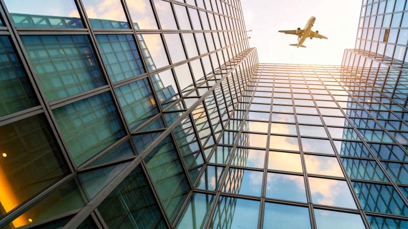 玻璃幕墙高楼间飞行的客机仰拍视角图片