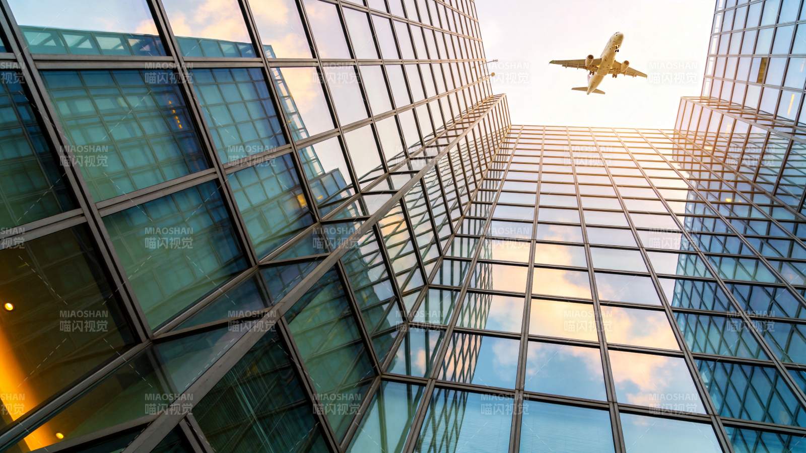玻璃幕墙高楼间飞行的客机仰拍视角图片