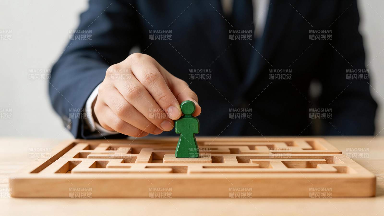 商务人士手持绿色人偶置于木质迷宫中央图片