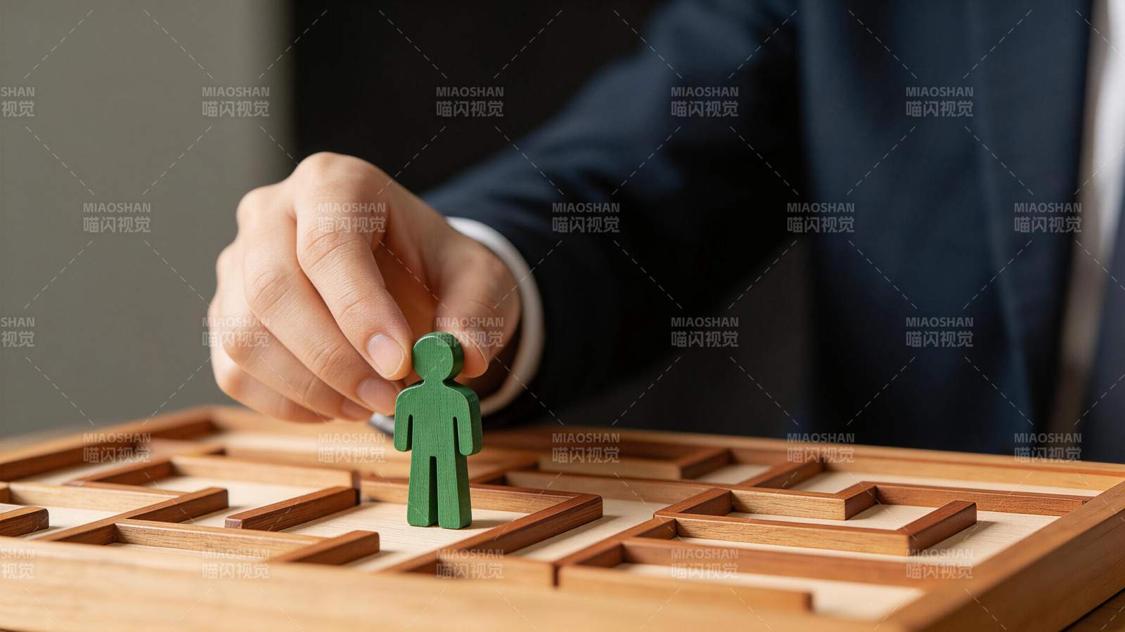 商务人士手持绿色人形棋子置于木质迷宫上图片