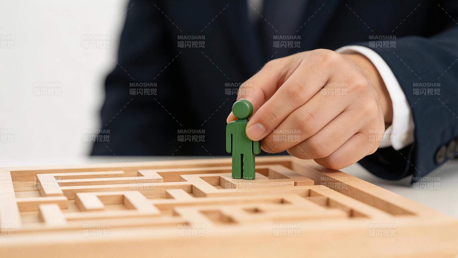 手握绿色人形棋子置于木质迷宫起点图片