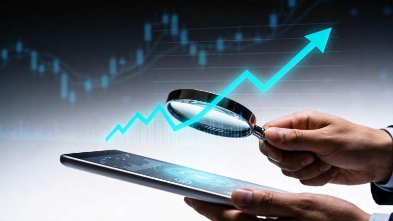 手持放大镜观察平板显示的上升趋势图表图片