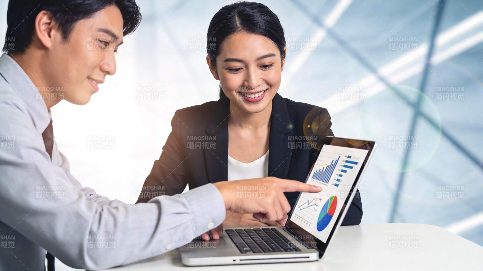 男女同事共同分析笔记本电脑上的数据图表图片