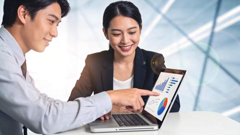 男女同事共同分析笔记本电脑上的数据图表图片