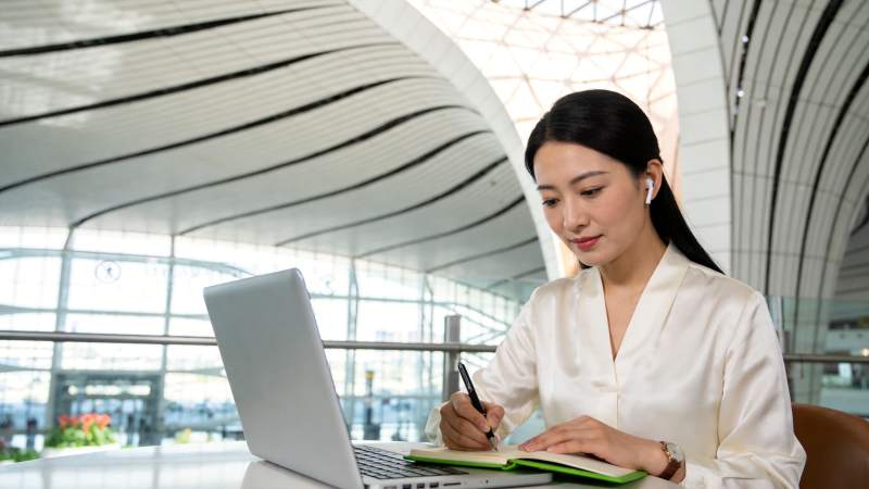 女性在现代化公共空间使用笔记本电脑记录笔图片