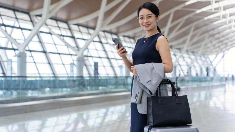 机场候机厅中手持手机的商务女性图片