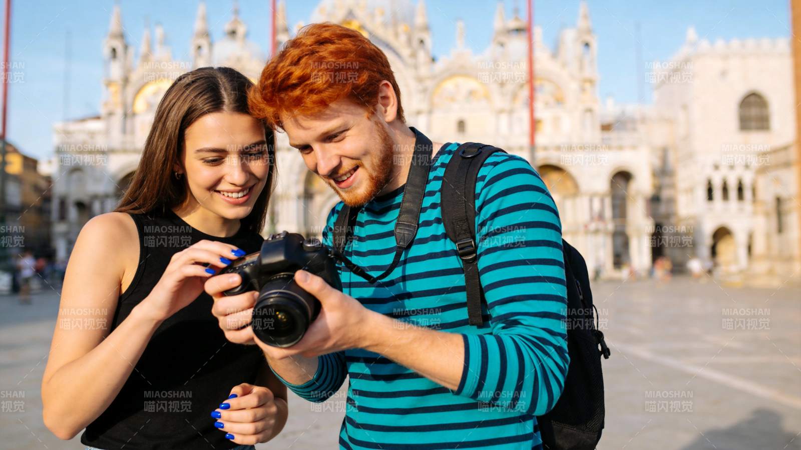 红发男子与女子在广场查看相机照片图片