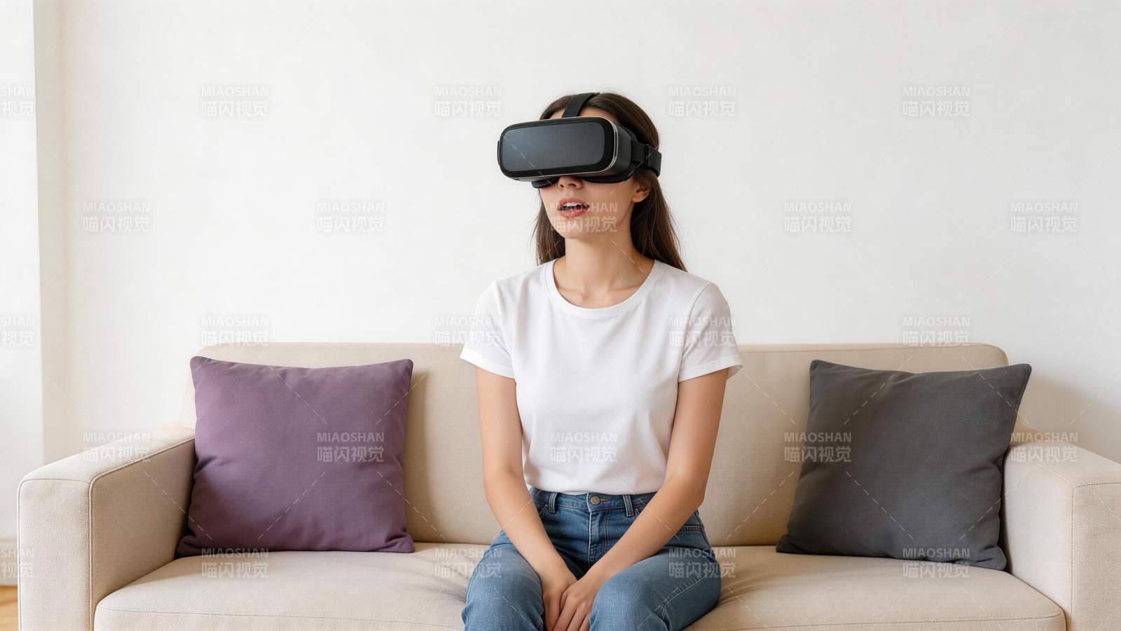 女子佩戴VR眼镜坐在米色沙发上体验虚拟现图片