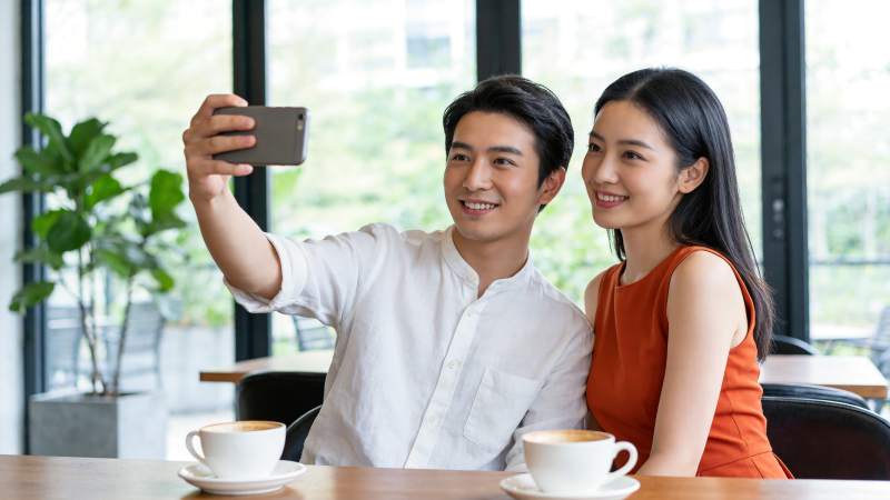 男女在咖啡馆用手机自拍合影图片