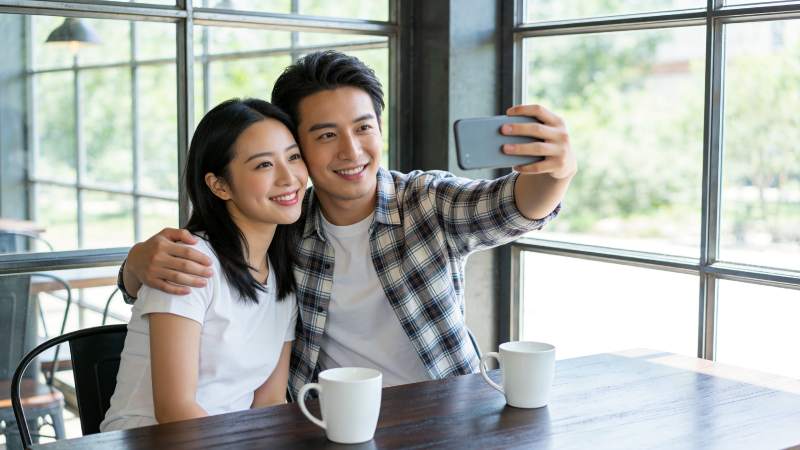 年轻男女在咖啡馆用手机自拍合影图片